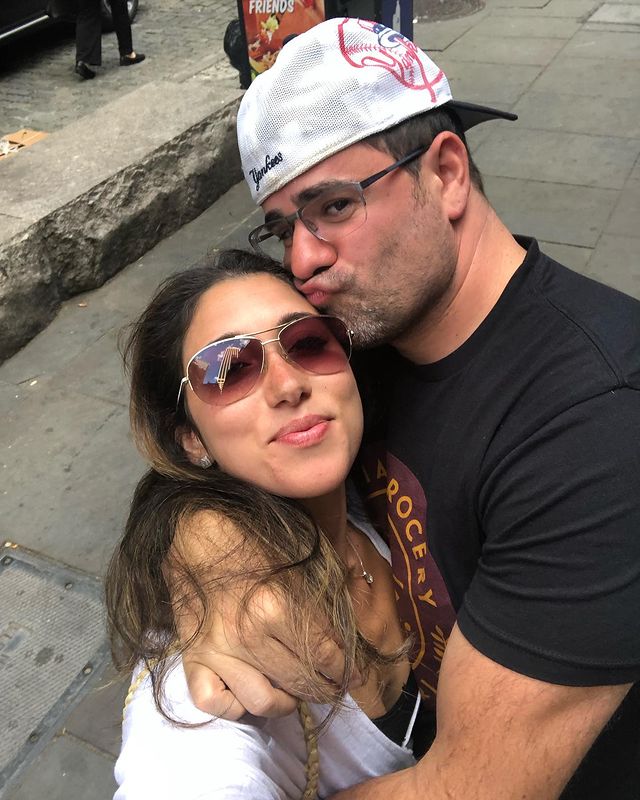 Yannis Pappas in a black t-shirt with his wife in a white cardigan.